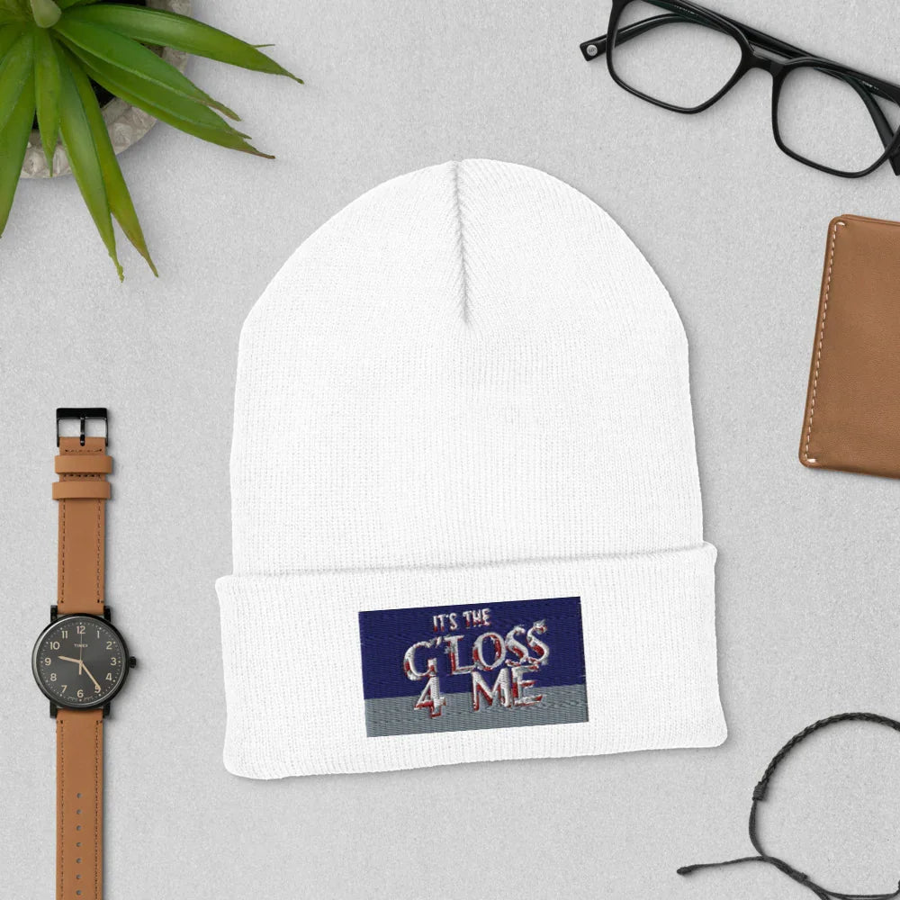 White knit beanie with 'It's the Gloss 4 Me' patch, styled with watch and glasses.