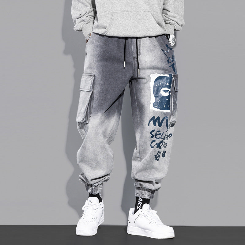 Gray cargo jogger pants with graffiti face print, side pockets, and casual streetwear style.
