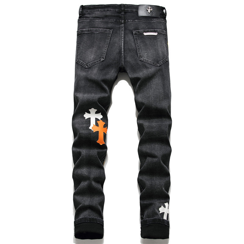 Black denim jeans with white and orange cross patches on the back legs